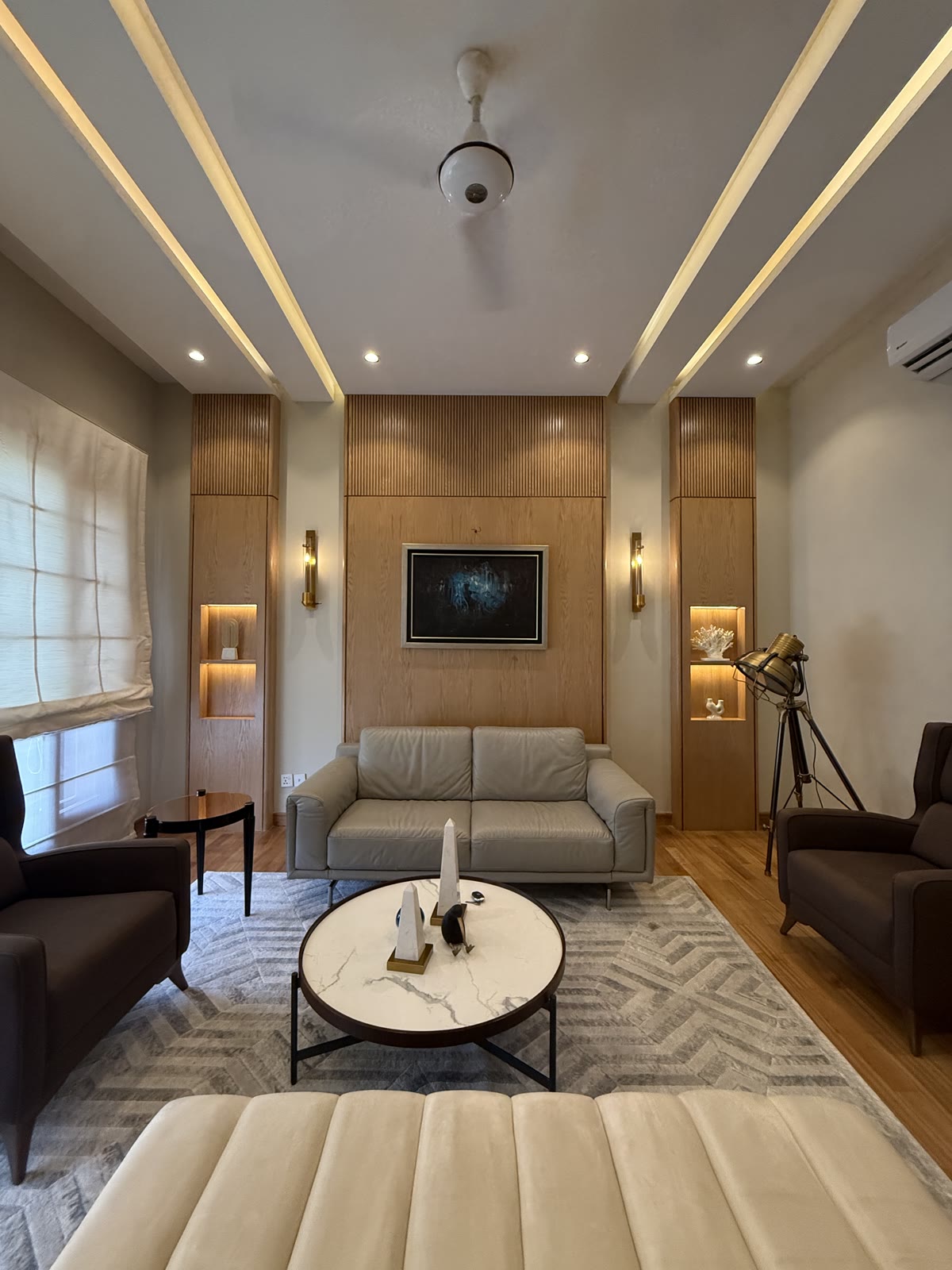 DA Elements timber-panelled living room with leather sofa and tripod lamp
